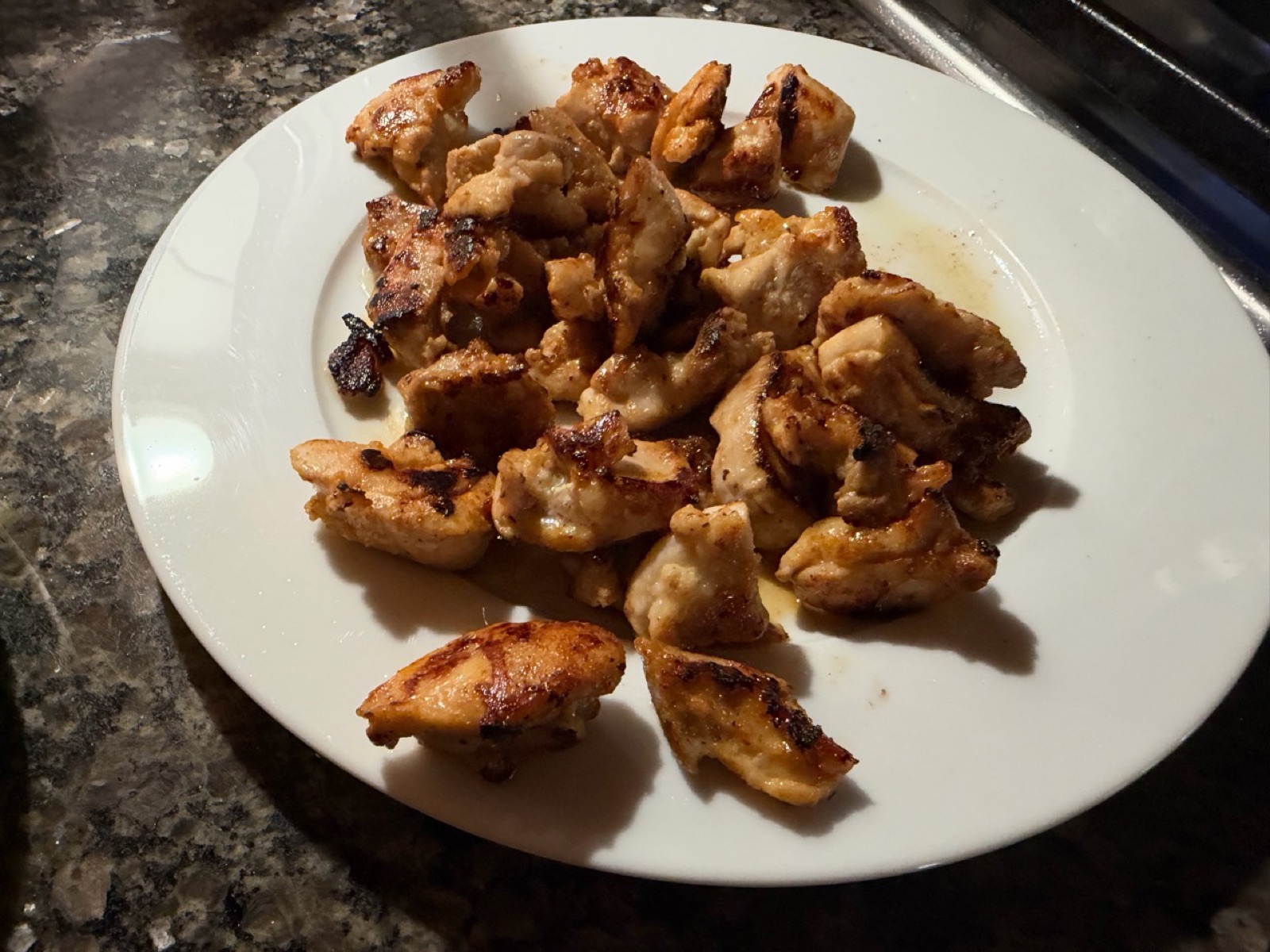 Browned yogurt-marinated chicken thigh pieces resting on a white plate.
